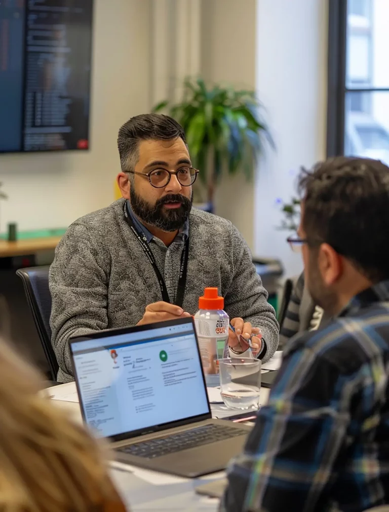 developer discussing with client & a loptop b/w them on desk
